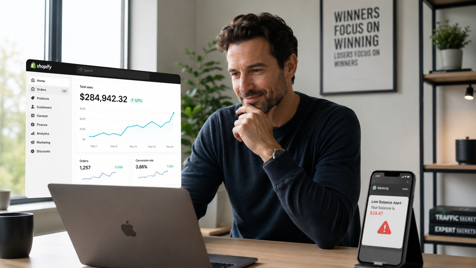 A professional man looking at his laptop screen displaying Shopify sales data alongside a mobile banking alert.